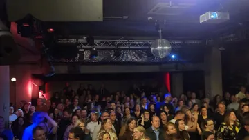 Menschenmenge tanzt in einem dunklen Club.