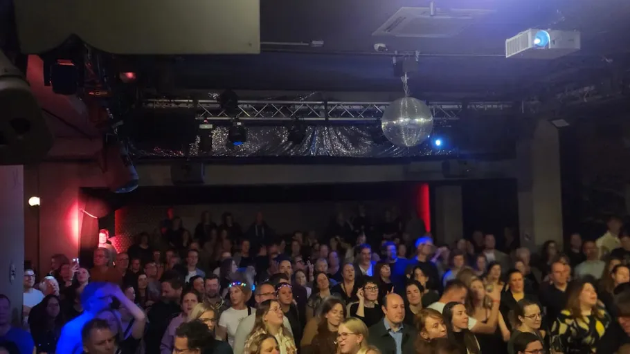 Crowd dance at a dimly lit club.