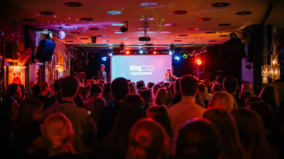 Menge genießt Karaoke in lebendigem, buntem Veranstaltungsort.