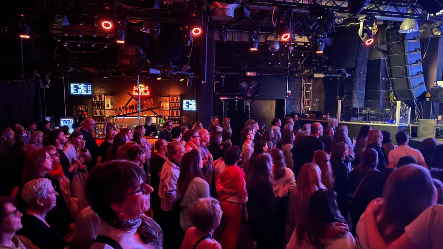 Crowd watching performance in dimly lit venue.