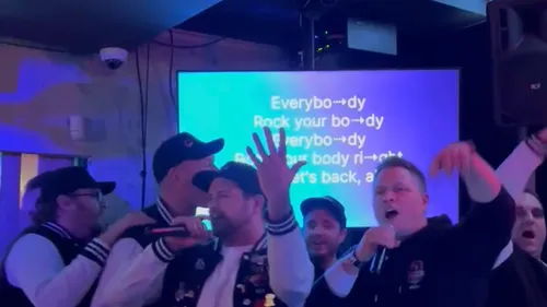 Group singing karaoke with lyrics on screen.