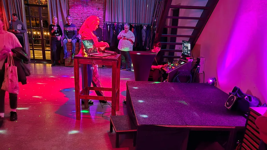 Person DJing at an indoor event with lighting.