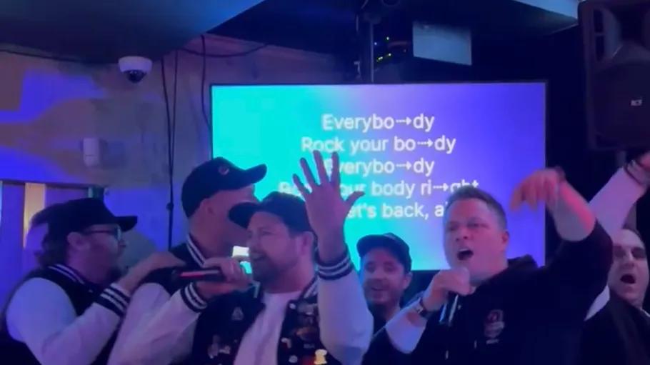 Group singing karaoke, with lyrics on screen.