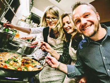 Cooking people prepare a dish together in the kitchen.