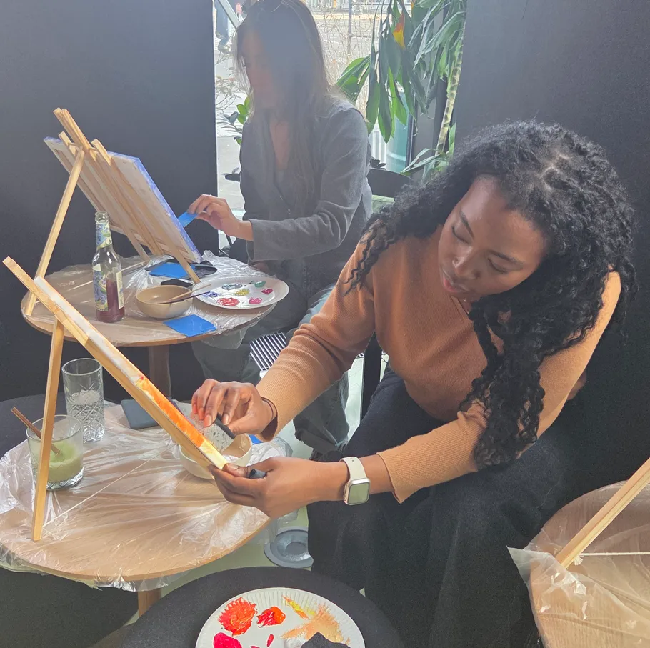 Women painting on canvases in a studio.