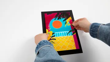 Hands holding colorful landscape artwork.