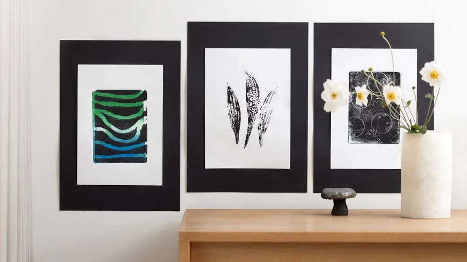 Three abstract artworks on wall above table.