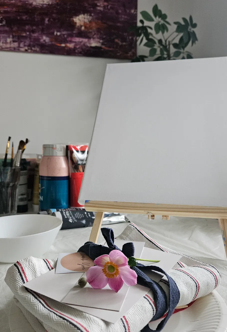 Blank canvas on easel, art supplies nearby.