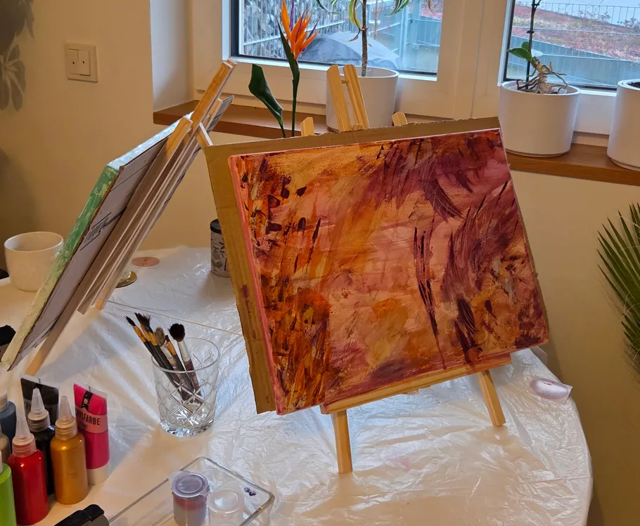 Abstract painting on easel near window.