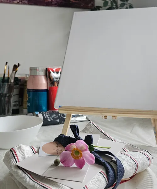 Blank canvas on easel with painting supplies.