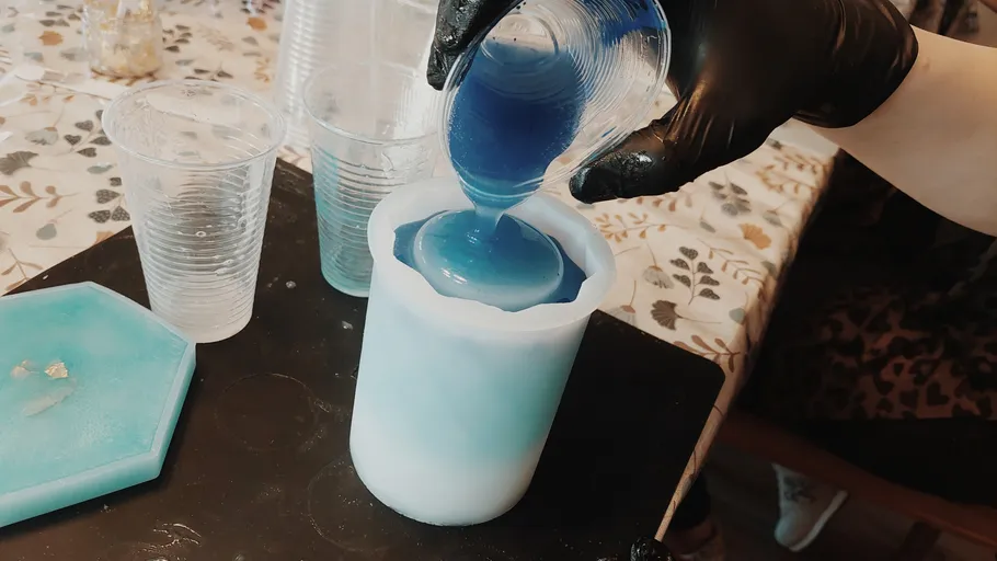 Person pours blue resin into a mold.