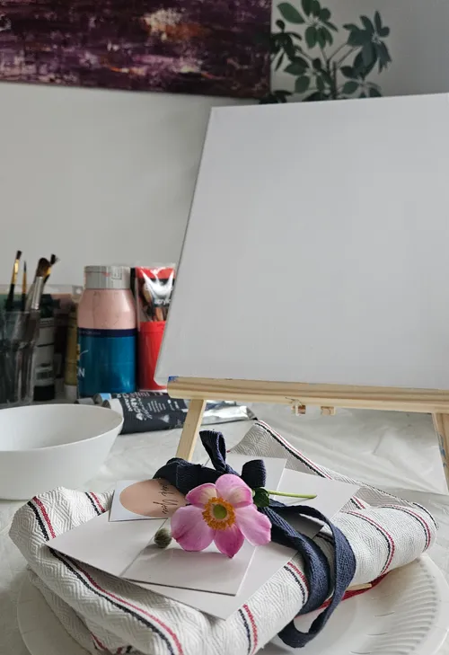 Kunstmaterialien und leere Leinwand auf einem Tisch.