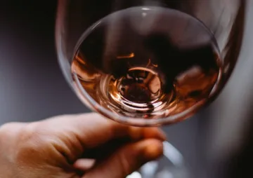 Ein Glas Roséwein wird von einer Hand gehalten.