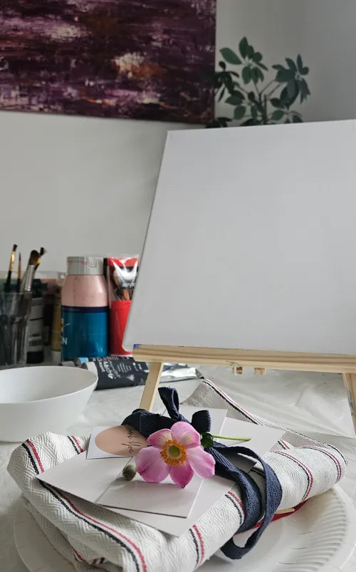 Canvas on easel with art supplies nearby.