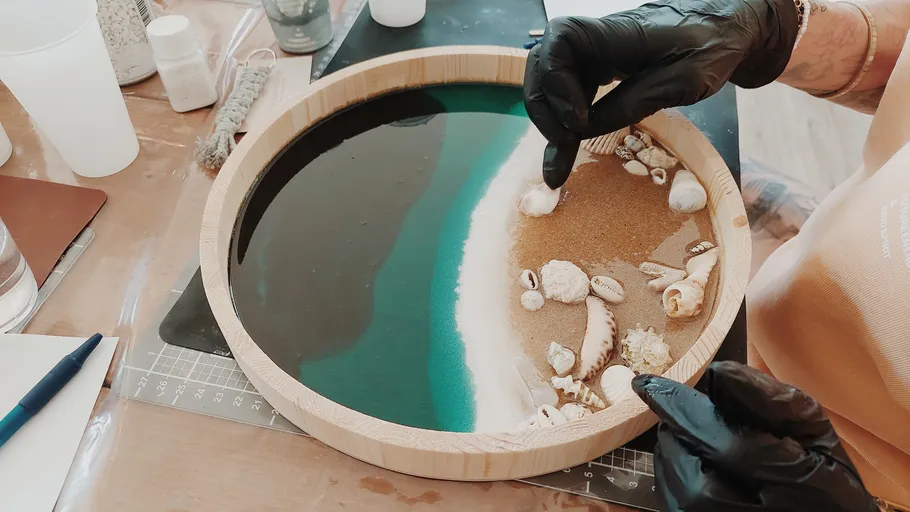 Person crafting beach scene resin art.