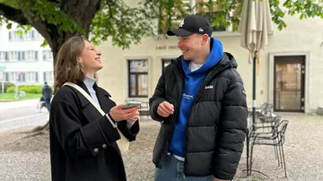 Zwei Personen lachen vor einem Café.