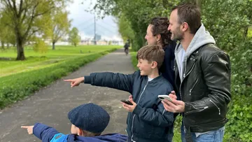 Family pointing in park with phones.