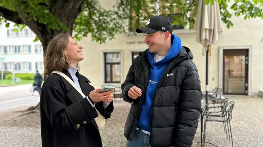 Two people smiling and talking outdoors.