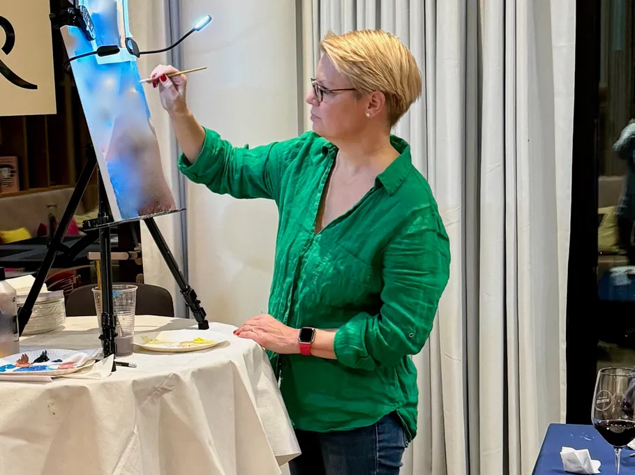 Woman painting on canvas in a room.