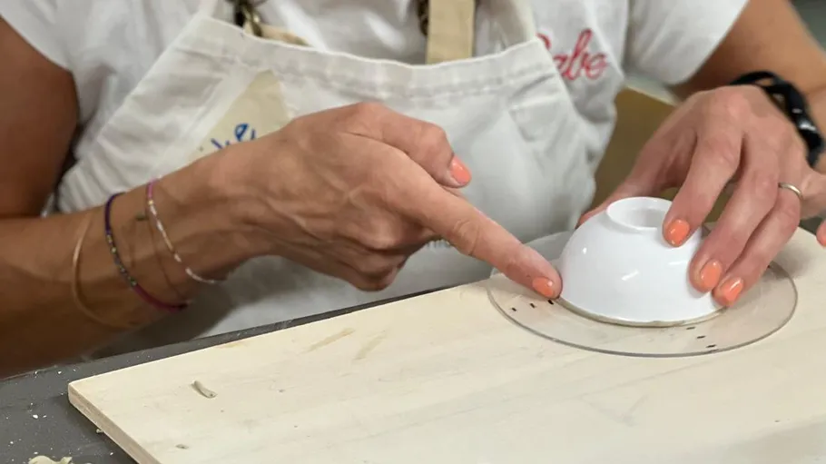 Hände zeichnen Kreis auf Holz mit Schüssel.