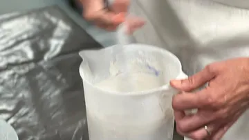 Person mixing batter in a plastic jug.