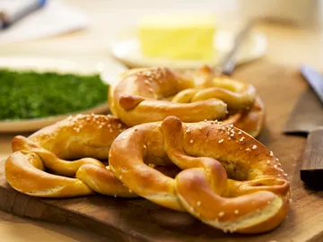 Pretzels lie on a wooden board in a warm environment.