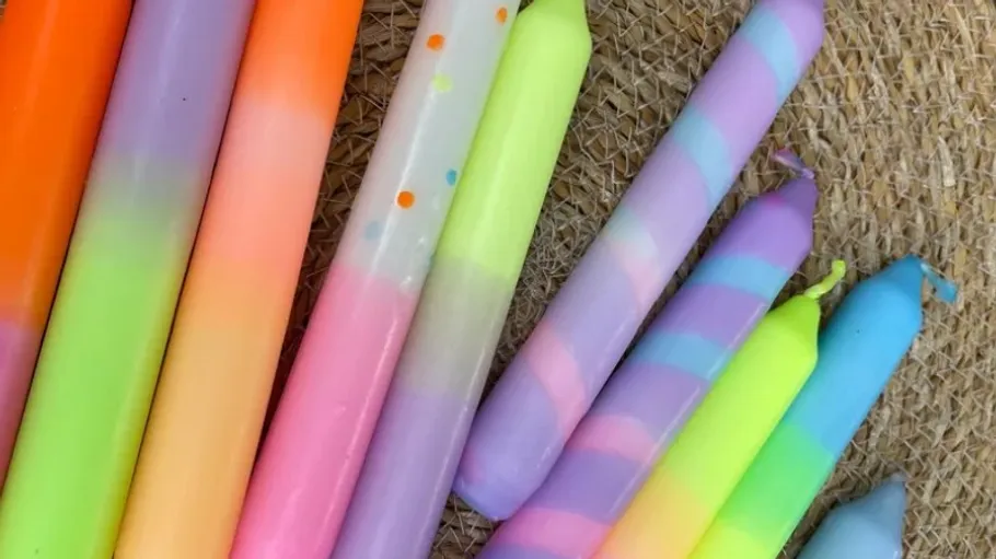 Colorful candles on a woven surface.