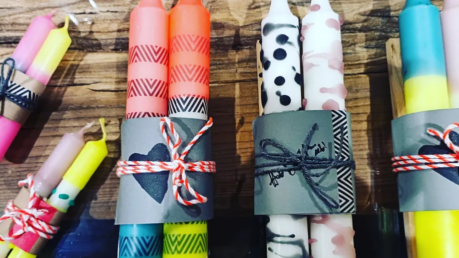 Colorful candles wrapped in twine on wooden table.