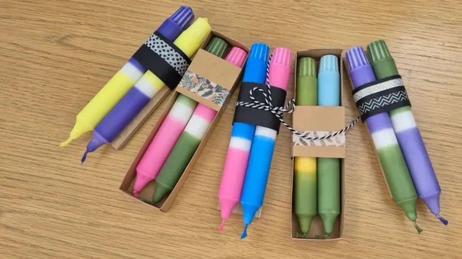 Colorful candles wrapped in paper on table.