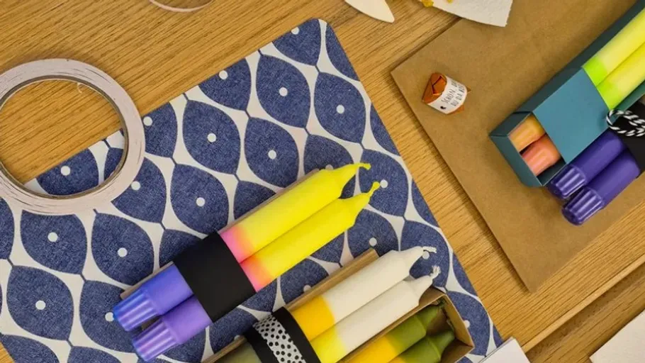 Colorful candles on wood and patterned mats.