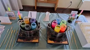 Colorful wax jars on stoves in workshop setting.