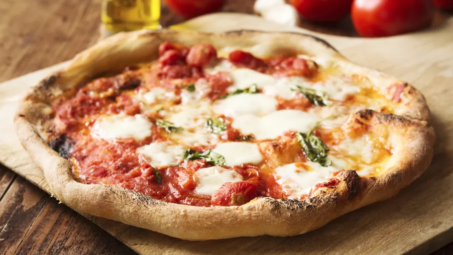 Pizza Margherita mit Basilikum auf Holzbrett.