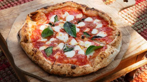 Pizza Margherita on wooden board outdoors.