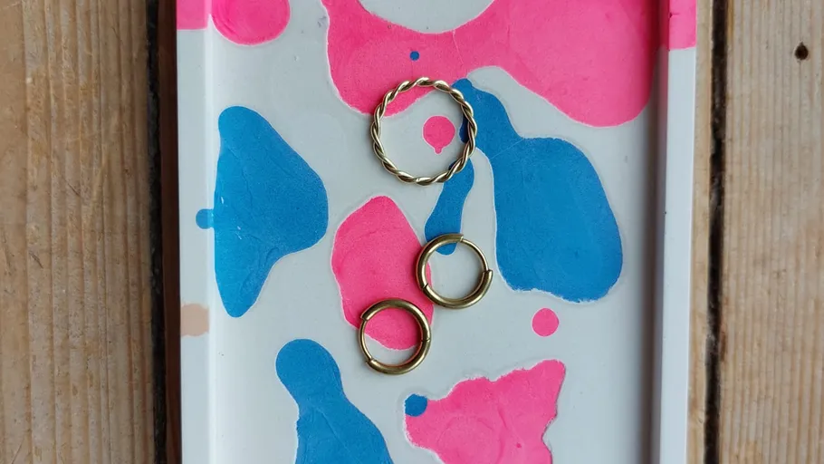 Three gold rings on colorful tray.