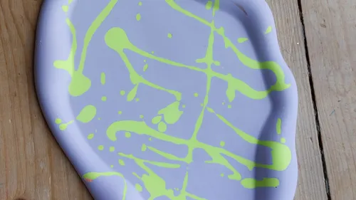 Purple clay tray with green paint splatters.