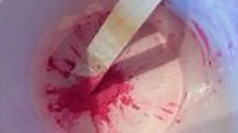 Pink mixture stirred in a container.