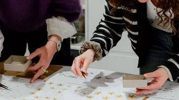 Two people crafting with paper and decorations.