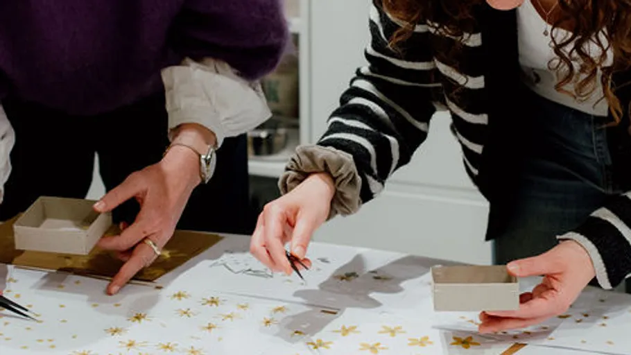 Zwei Personen basteln mit Papier und Dekorationen.
