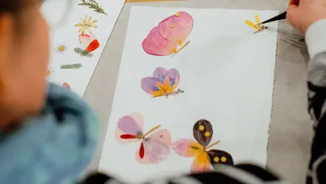 Person painting colorful flowers on paper.