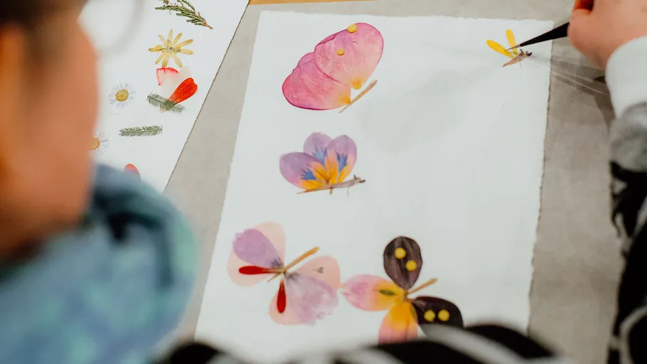 Person painting colorful flowers on paper.