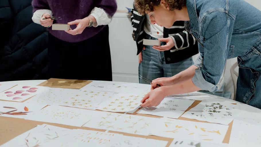 People examining floral designs on a table.