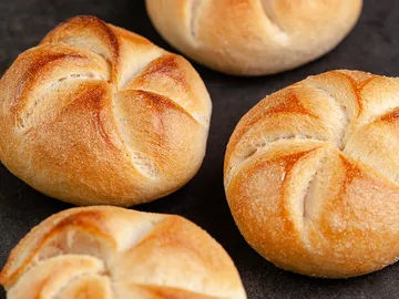 Brötchen liegen auf einer dunklen Oberfläche und glänzen.