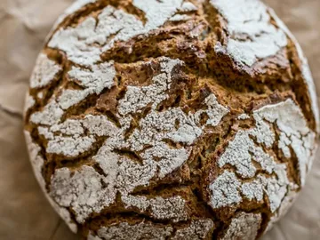 Rundes Brot mit rissiger Kruste auf braunem Papier.