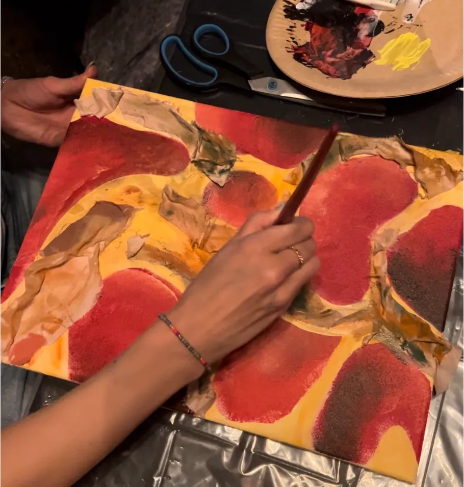 Person painting abstract art on canvas.