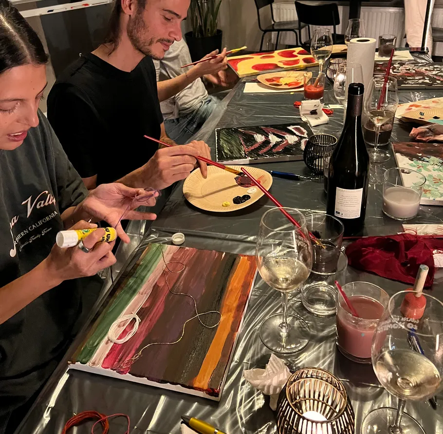 People painting at a table with drinks.