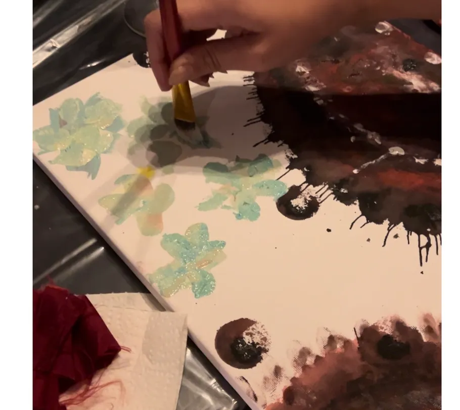 Hand painting flower shapes on canvas.