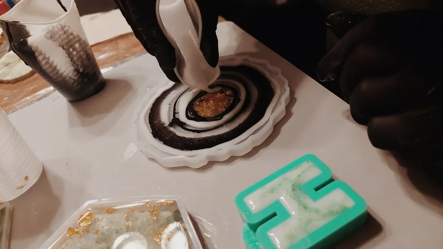 Hands pouring resin into circular mold.