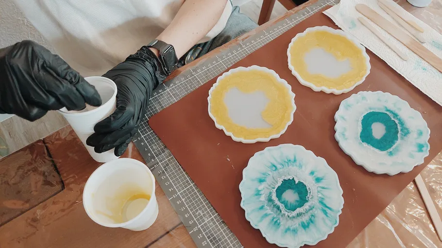 Person pouring resin into molds on table.