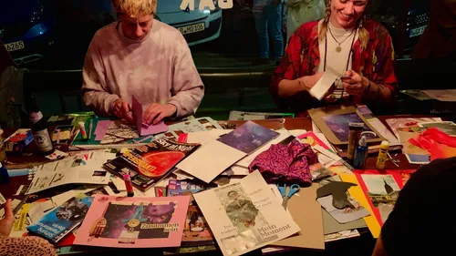 Two people crafting at a cluttered table.