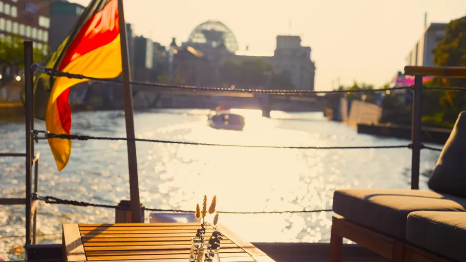 Sonniger Flussblick vom Boot mit deutscher Flagge.